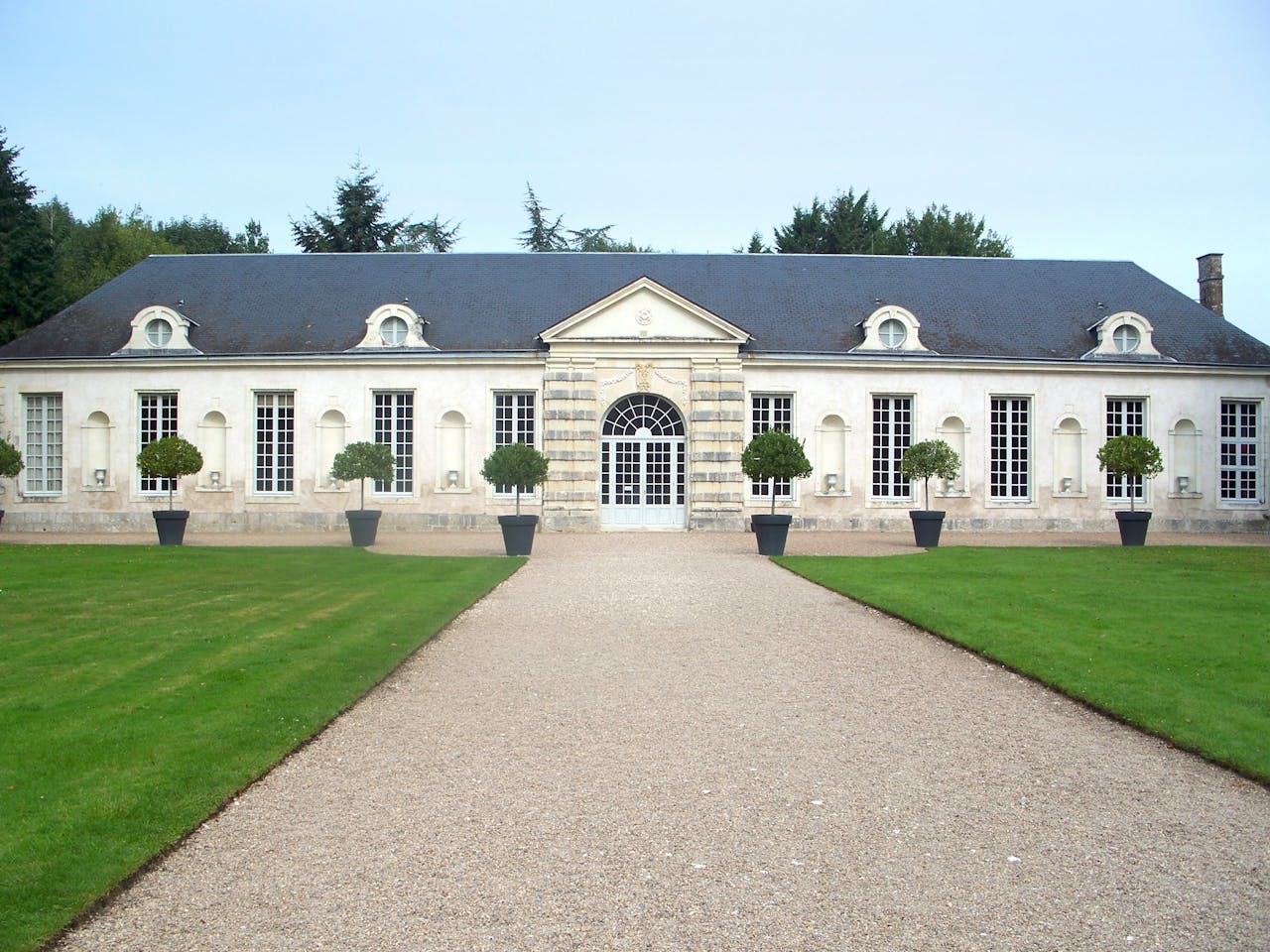Historic French manor entrance with elegant classical architecture and manicured gardens.